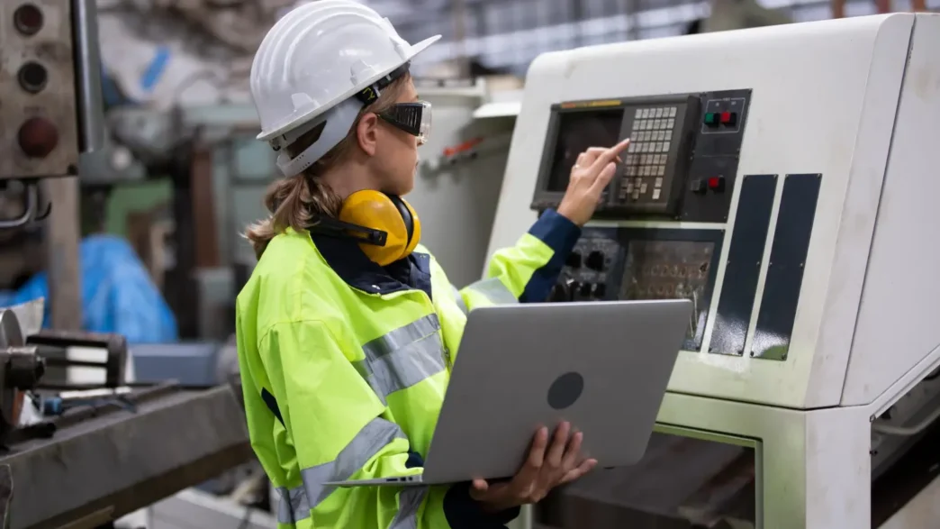 Engenheira de segurança realiza parametrização de máquina CNC, integrando práticas da NR 12 com análise digital para garantir operação segura e eficiente.