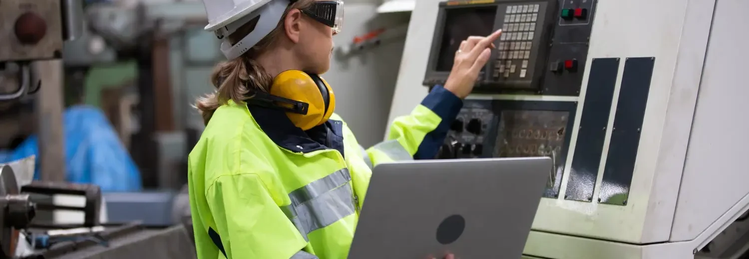 Engenheira de segurança realiza parametrização de máquina CNC, integrando práticas da NR 12 com análise digital para garantir operação segura e eficiente.