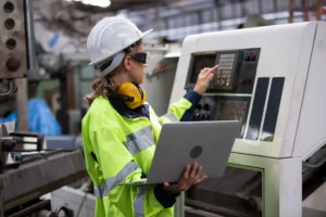 Engenheira de segurança realiza parametrização de máquina CNC, integrando práticas da NR 12 com análise digital para garantir operação segura e eficiente.