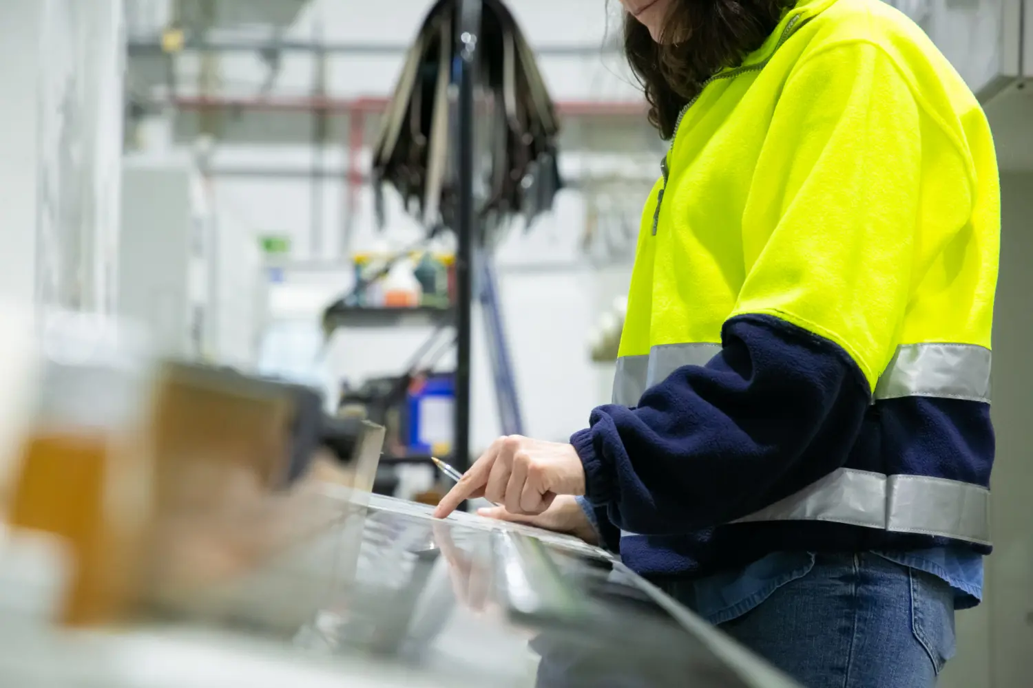 Profissional opera sistema de controle de máquina com interface digital, aplicando práticas da NR 12 para segurança e eficiência no ambiente industrial.