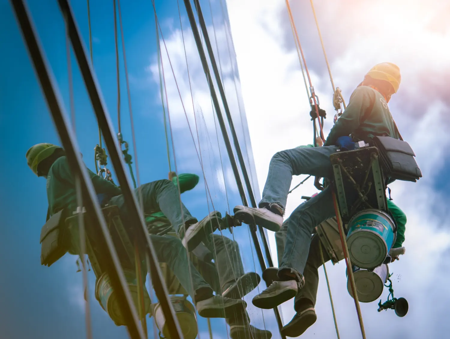 Operadores executando trabalho em fachada com técnicas de acesso por corda.