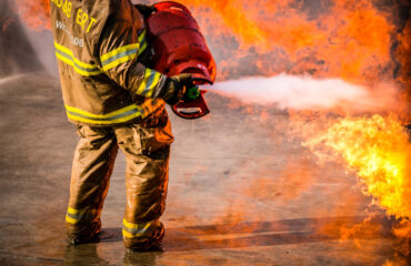 Seção baixa de bombeiro pulverizando extintor em chamas. Seção baixa de bombeiro pulverizando extintor em chamas. - Consultoria NR 23