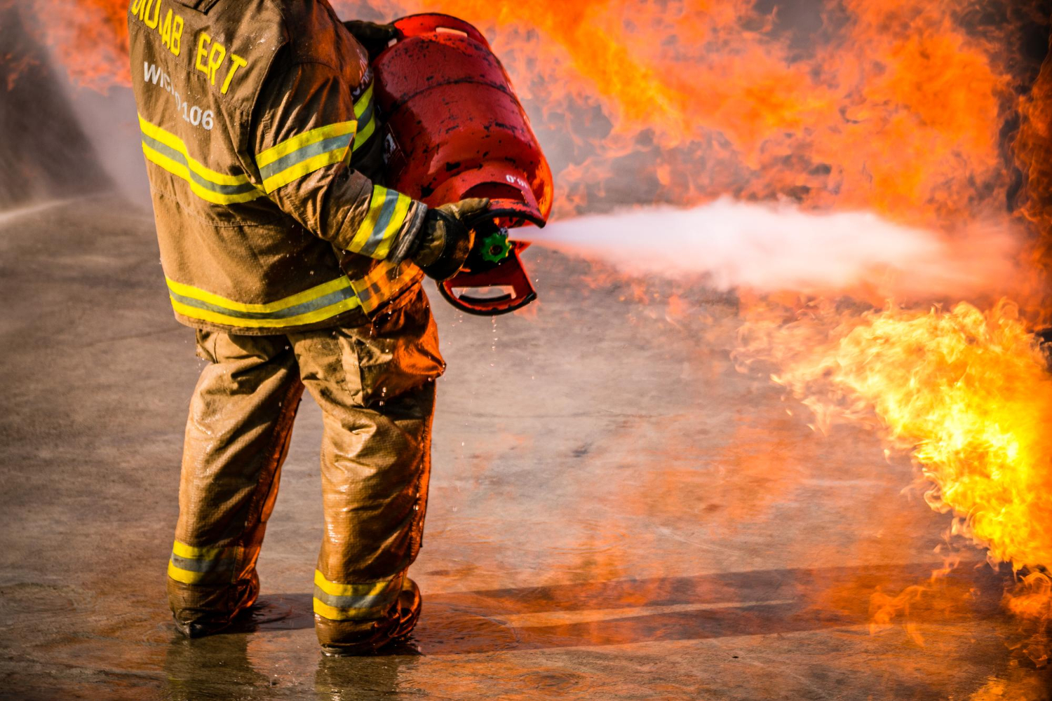 Seção baixa de bombeiro pulverizando extintor em chamas. - Consultoria NR 23