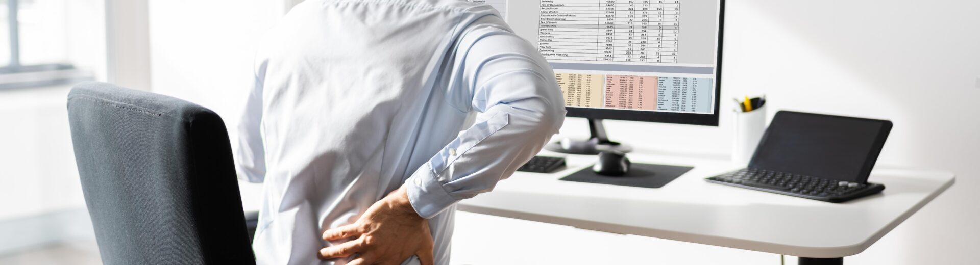 trabalhador sentado diante de um computador em uma estação de trabalho.