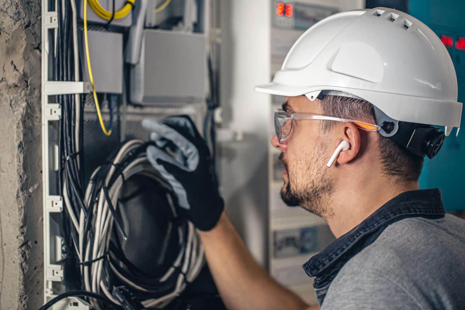 Técnico inspeciona o agrupamento de cabos em painel elétrico, observando organização, fixação e integridade física.