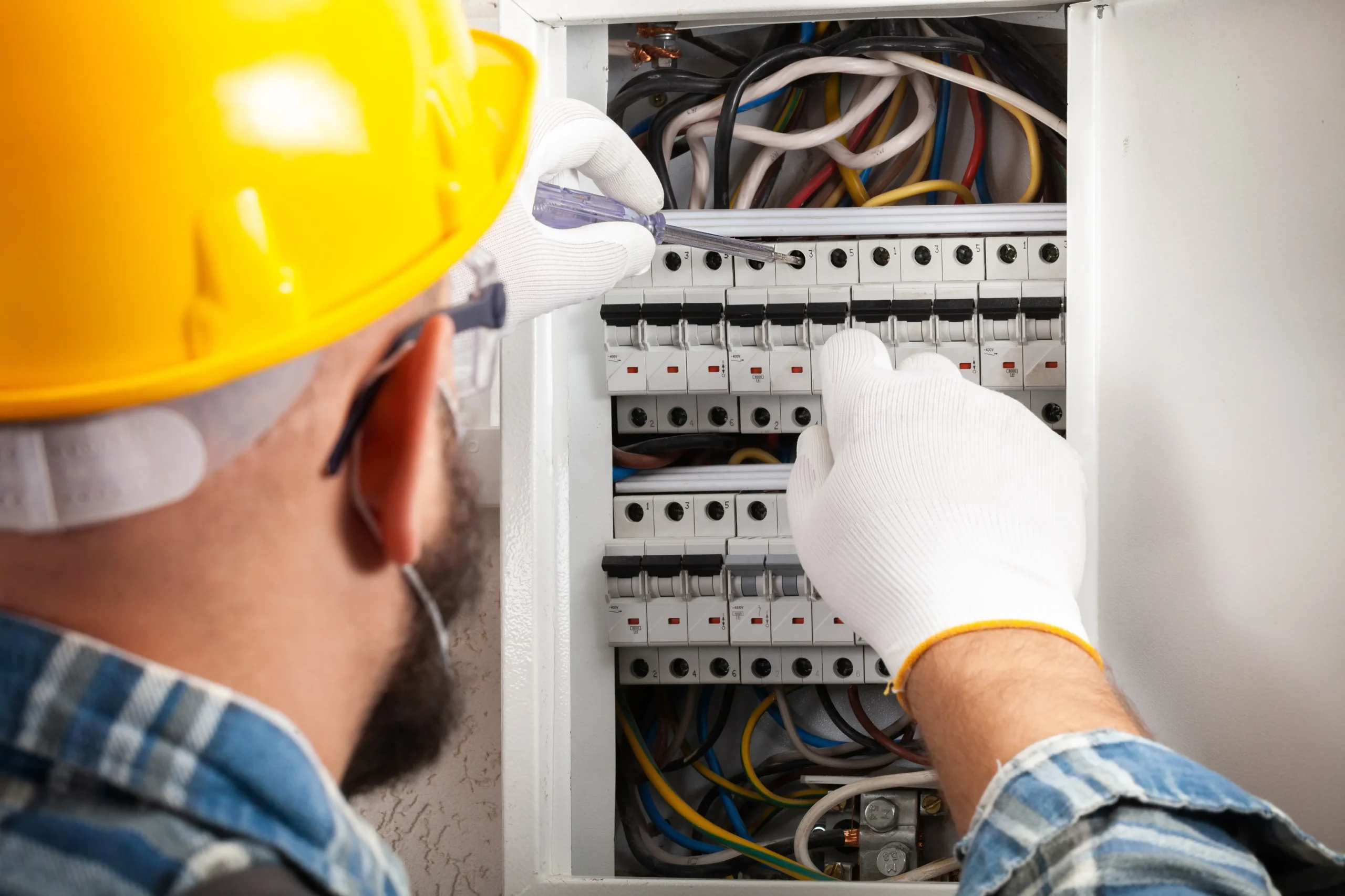 Technical intervention in a circuit breaker panel with multiple circuits, performed using PPE and manual tools. The organization of conductors and the absence of exposed wires are clear indicators of compliance with NR 10.