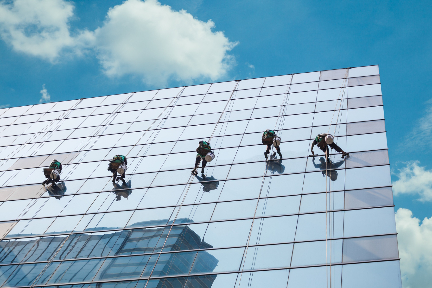 Rope access techniques with full PPE on a building facade.