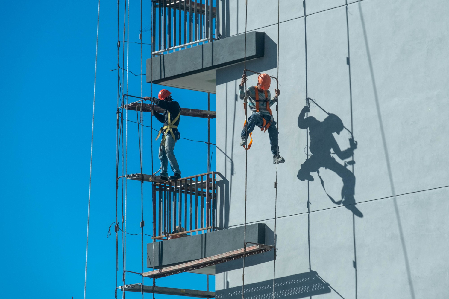 Vertical operation using ropes and suspended scaffold. Mandatory PPE ensures safety during height work.