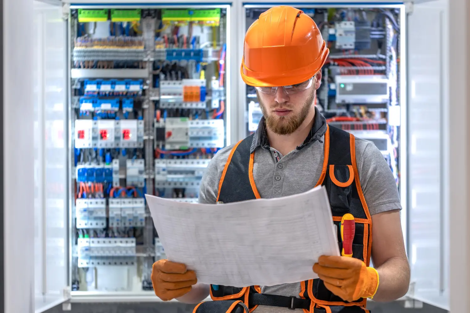 Engenheiro eletricista avalia os diagramas unifilares diante do painel principal, validando o estado operacional e a conformidade das instalações para emissão do relatório técnico NR 10.