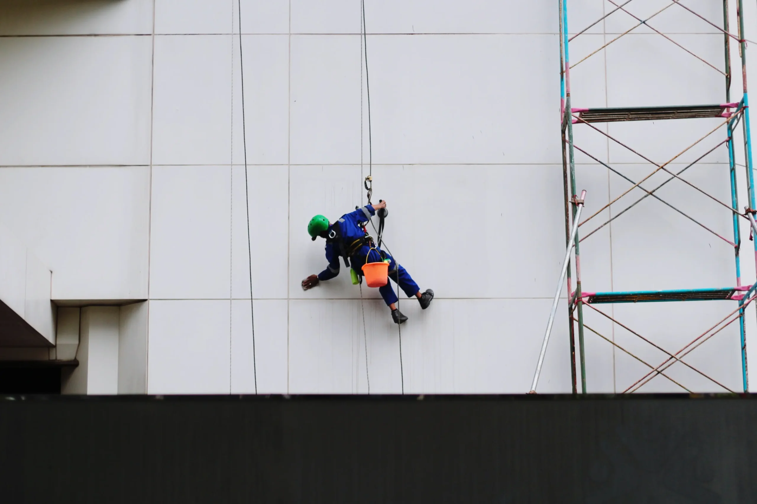 Técnico capacitado realiza atividade em altura com cadeira suspensa, utilizando sistema de ancoragem independente, trava de segurança e EPIs adequados conforme NR 18. 