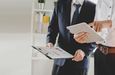 job-training-new-manager-boss-standing-teaching-online-work-with-mobile-tablet-young-intern-apprentice-learning-statistics-chart-working-office