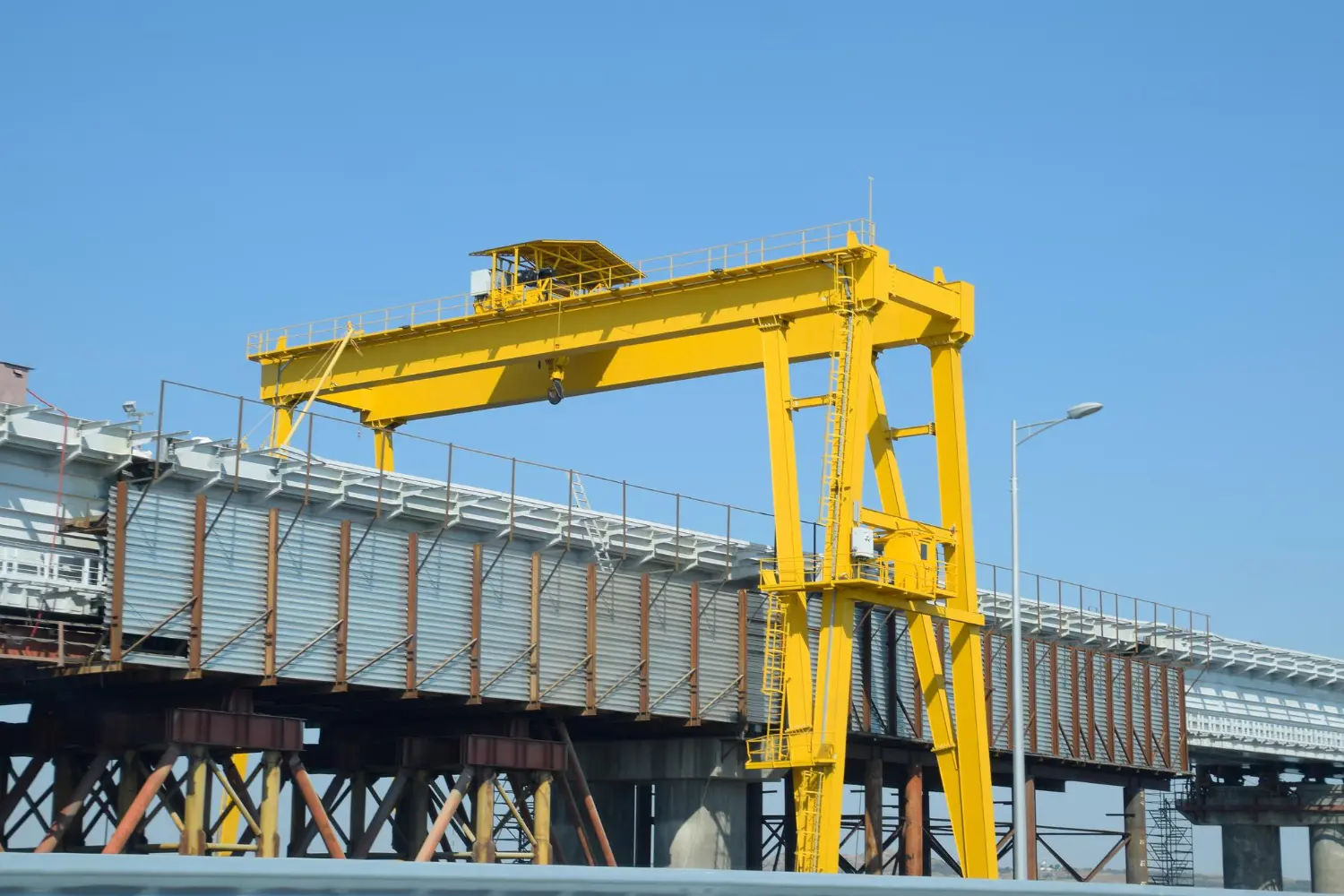 Pórtico sobre trilhos ferroviários. A manutenção deve focar em alinhamento, sensores e sistema de translação.