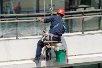 Execução de tarefa em fachada com cadeira suspensa: a segurança do operador depende da correta ancoragem, inspeção de equipamentos e aplicação das normas NR 18 e NR 35.