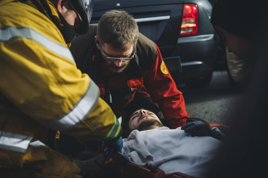 Paramedicos prestando primeiros socorros a um homem ferido. - Curso de Primeiros Socorros