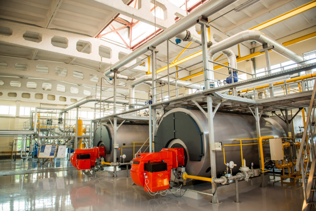 Vasos de pressão do tipo horizontal em sala de caldeiras industrial. Os sistemas estão conectados a tubulações de gás, válvulas, painéis de controle e componentes auxiliares - Curso Vaso de Pressão NFPA 85 e CGA G-2.1