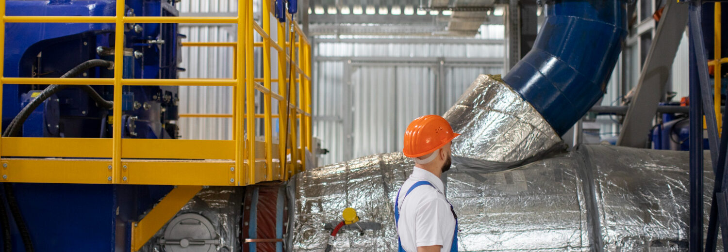 Profissional inspeciona um sistema pressurizado com isolamento térmico, em ambiente industrial.