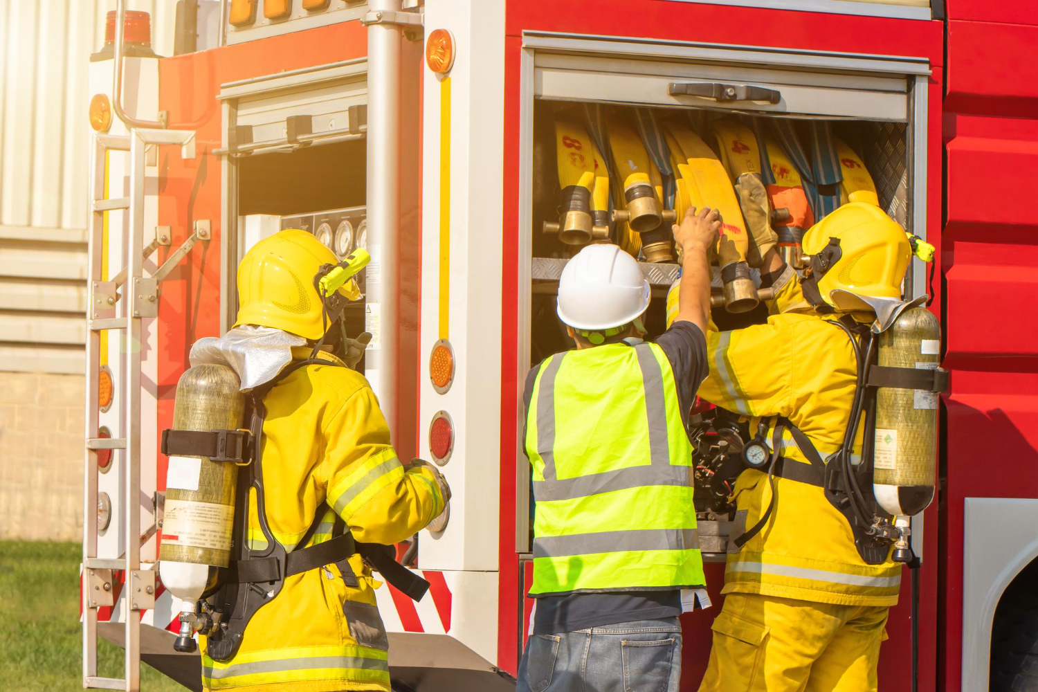 Bombeiros organizando mangueiras no caminhão de combate a incêndios, garantindo que todo o equipamento esteja pronto para a próxima emergência.