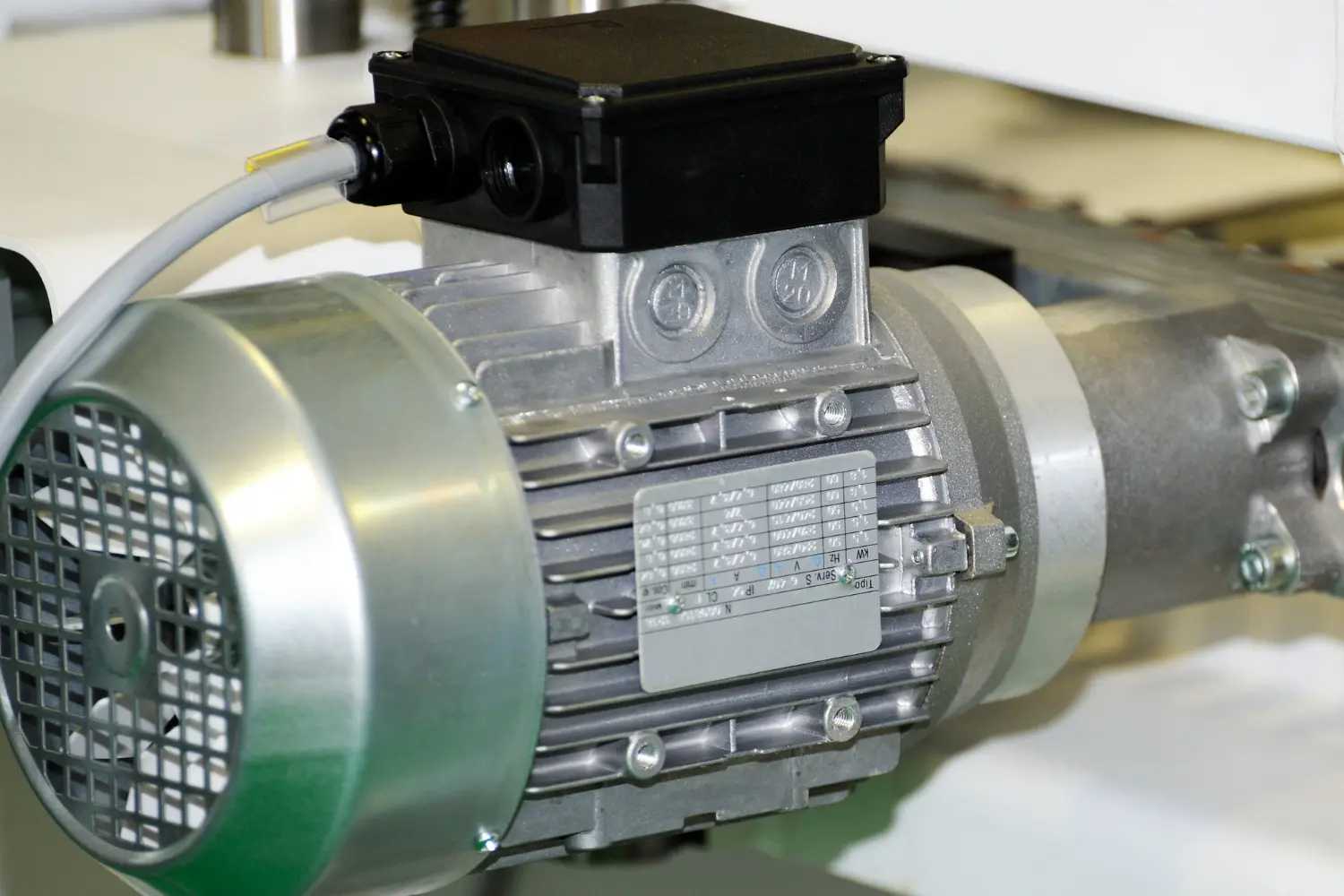 Motor industrial com placa de dados técnicos evidenciada. A leitura correta dessas informações é essencial para os ensaios de resistência, isolação, torque e desempenho térmico. A inspeção com base na NBR IEC 60034 valida a compatibilidade do equipamento com sua aplicação.