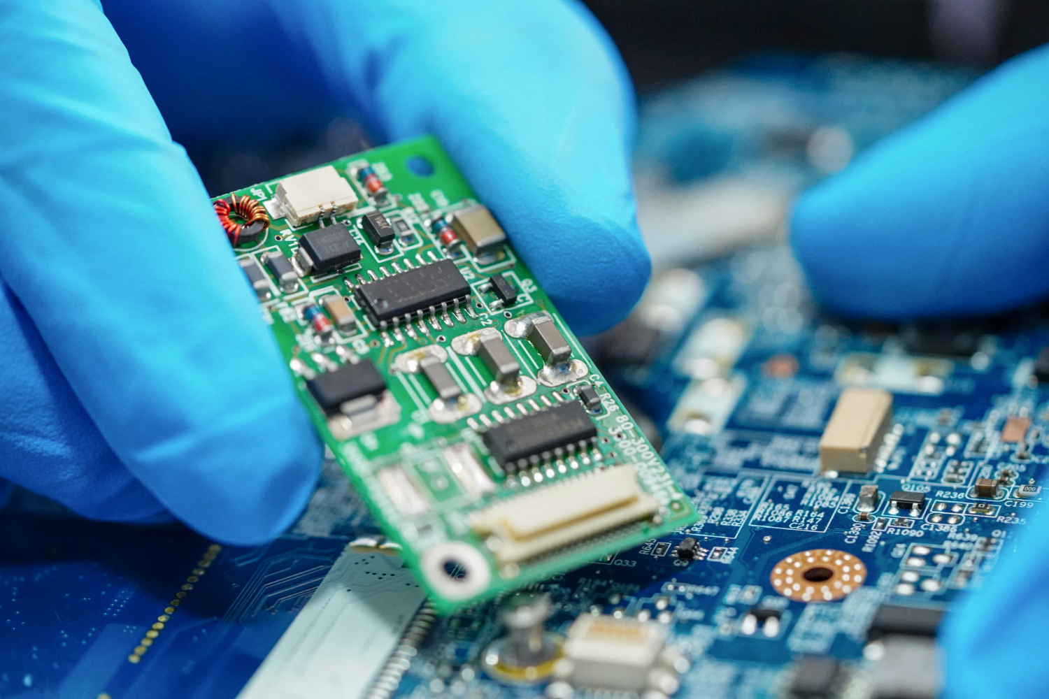 Placa de circuito sendo manuseada com cuidado, ilustrando o processo de montagem ou reparo de componentes essenciais em drives elétricos, com foco na precisão e no uso de equipamentos avançados. - Curso Manutenção Drives Elétricos.