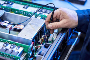 Técnico inspecionando e testando uma unidade de drive elétrico, destacando a importância da manutenção e calibração para garantir a eficiência e segurança operacional. - Curso Manutenção Drives Elétricos.