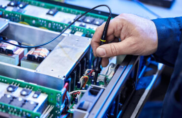 Técnico inspecionando e testando uma unidade de drive elétrico, destacando a importância da manutenção e calibração para garantir a eficiência e segurança operacional. Técnico inspecionando e testando uma unidade de drive elétrico, destacando a importância da manutenção e calibração para garantir a eficiência e segurança operacional. - Curso Manutenção Drives Elétricos.