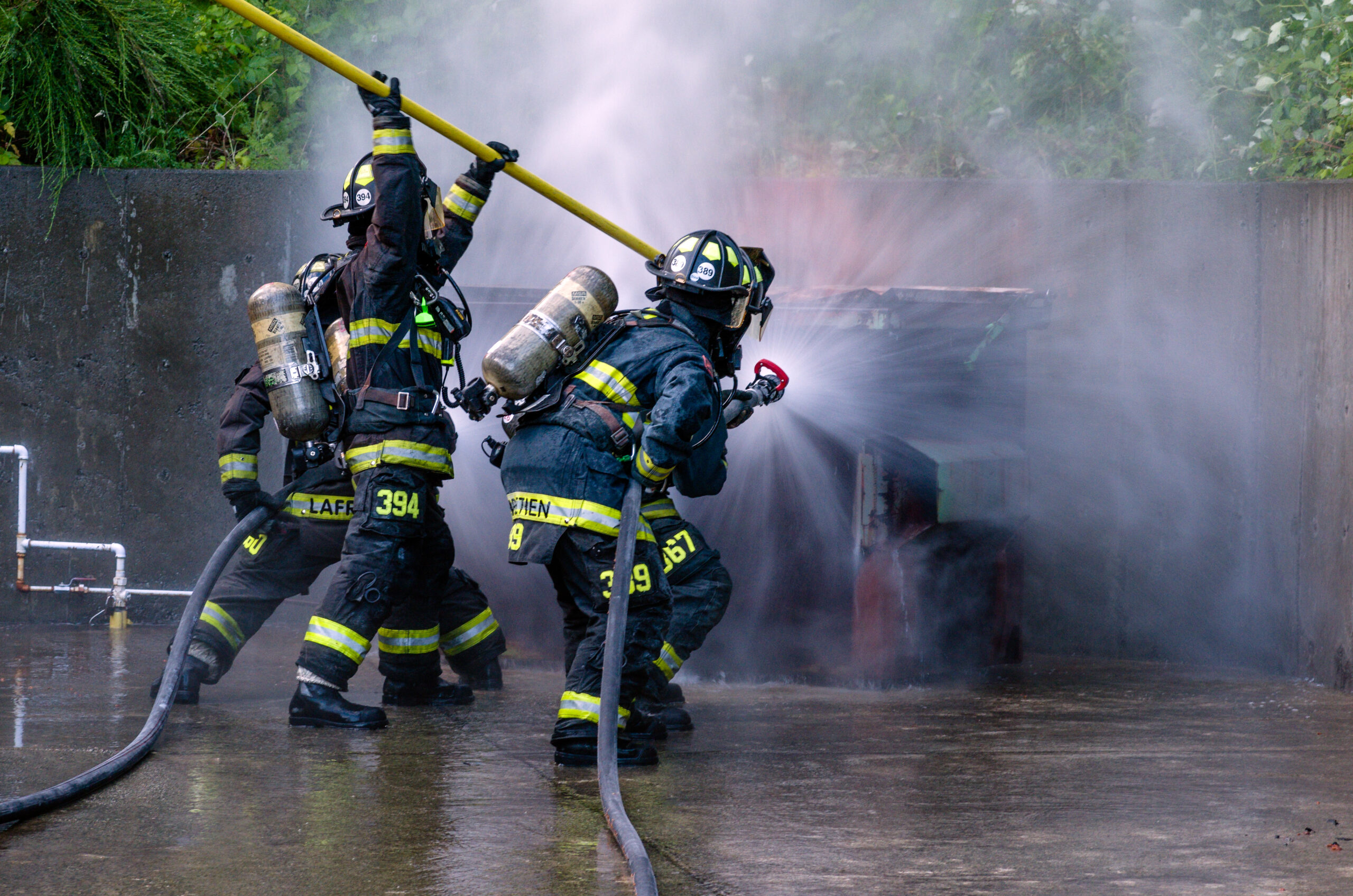Ventilação tática e ataque coordenado em espaço confinado, com SCBA e linha pressurizada.