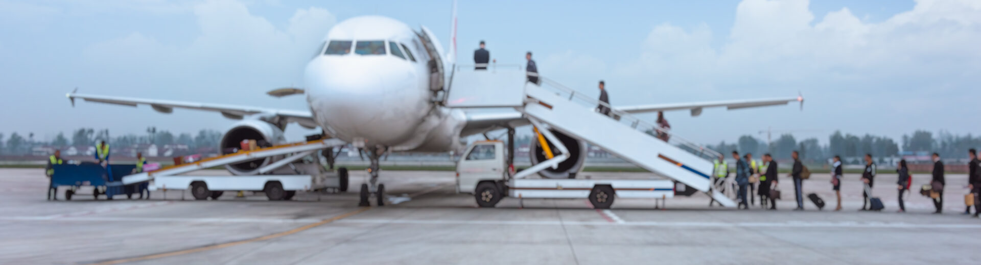 Processo de embarque realizado no pátio do aeroporto com o uso de escadas móveis, um método tradicional utilizado em operações onde mangas de embarque telescópicas não estão disponíveis ou viáveis, exigindo deslocamento externo dos passageiros entre o terminal e a aeronave. - Curso Operador Mangas Embarque.