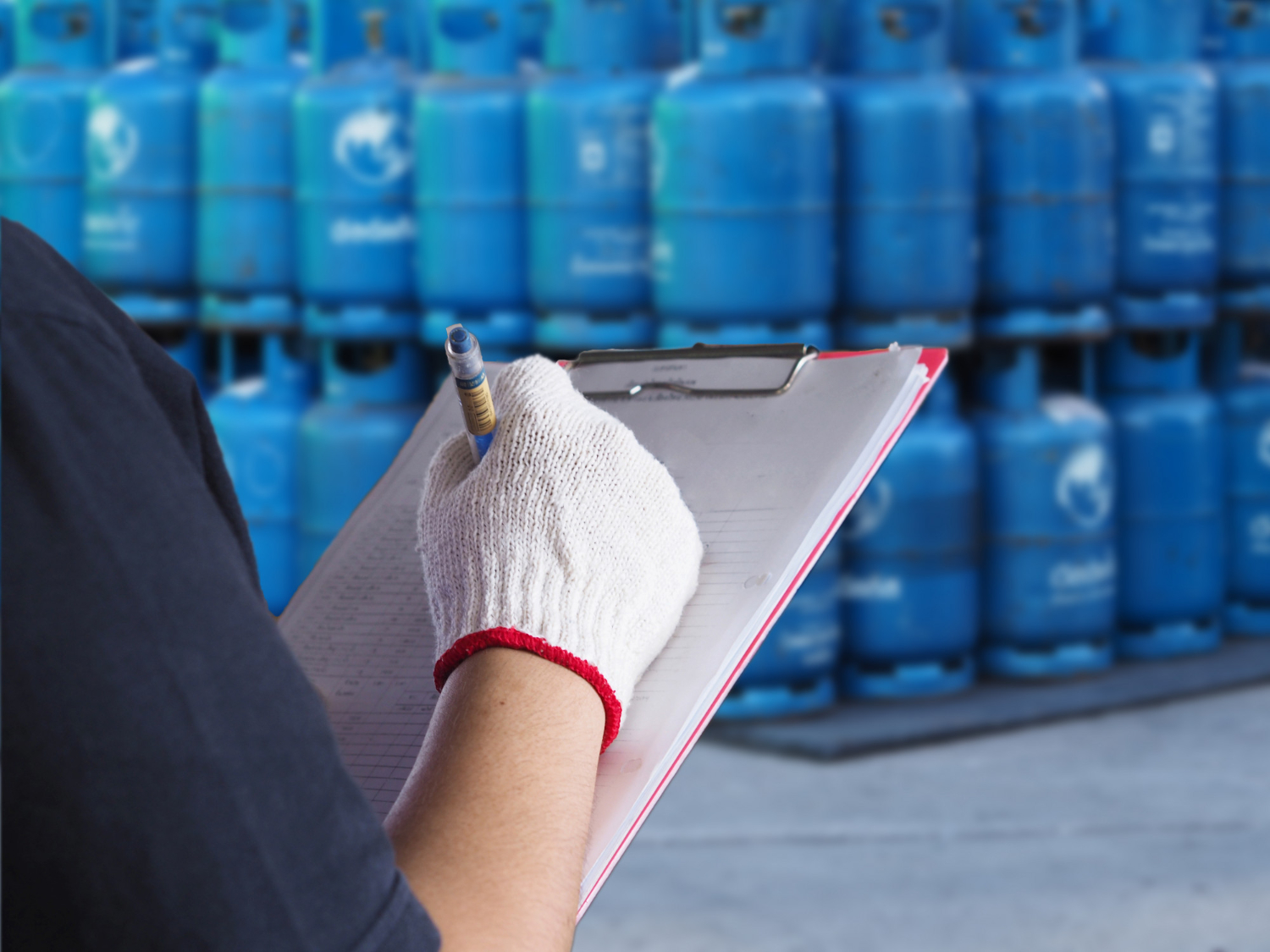 Profissional realizando inspeção com checklist de cilindros de gases industriais armazenados verticalmente. Equipamento de segurança e controle seguindo normas regulamentadoras. - Curso Legislação Cilindro Gases.