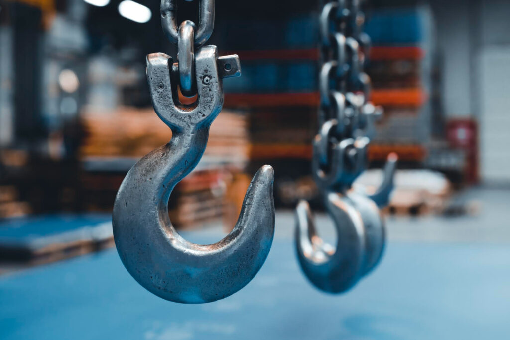 ganchos metálicos de içamento suspensos por correntes, em ambiente industrial - Curso Laudo Movimentação Cargas