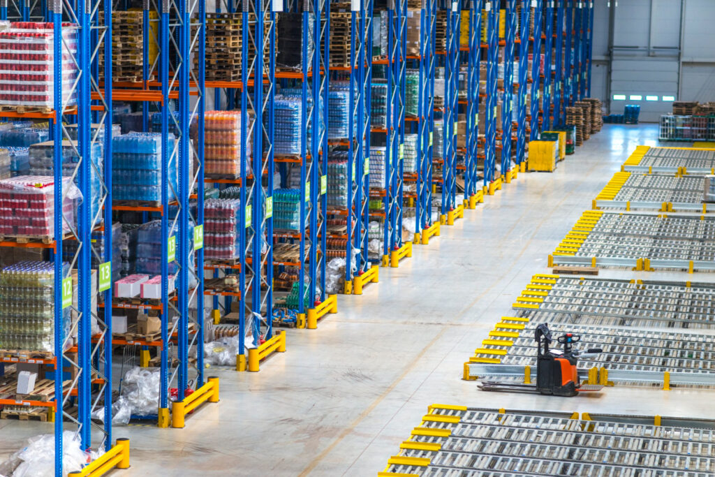 Interior do edifício do armazém de distribuição e grande área com pallets de metal e prateleiras de estocagem. - Curso Laudo de Pallets
