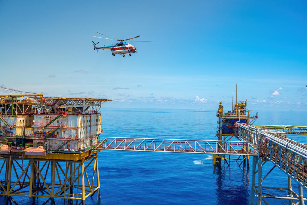 Helicóptero voando sobre uma enorme plataforma de perfuração de plataforma de petróleo offshore no campo de petróleo. - Curso NORMAM-27/DCP Helideques