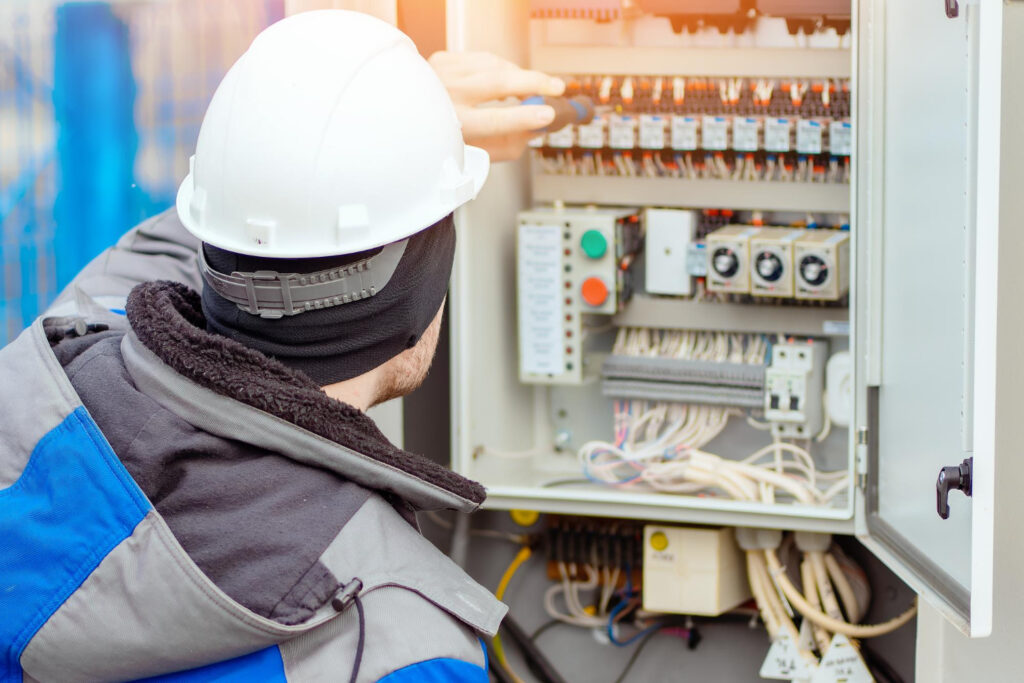 Técnico e frente a central elétrica, analisando dijuntores. - Consultoria NR 10