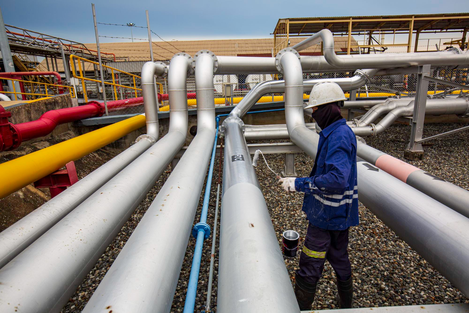 Trabalhador realiza a inspeção e manutenção de tubulações PRFV em uma instalação industrial. O revestimento e a proteção das tubulações são essenciais para garantir eficiência e segurança no transporte de fluidos.