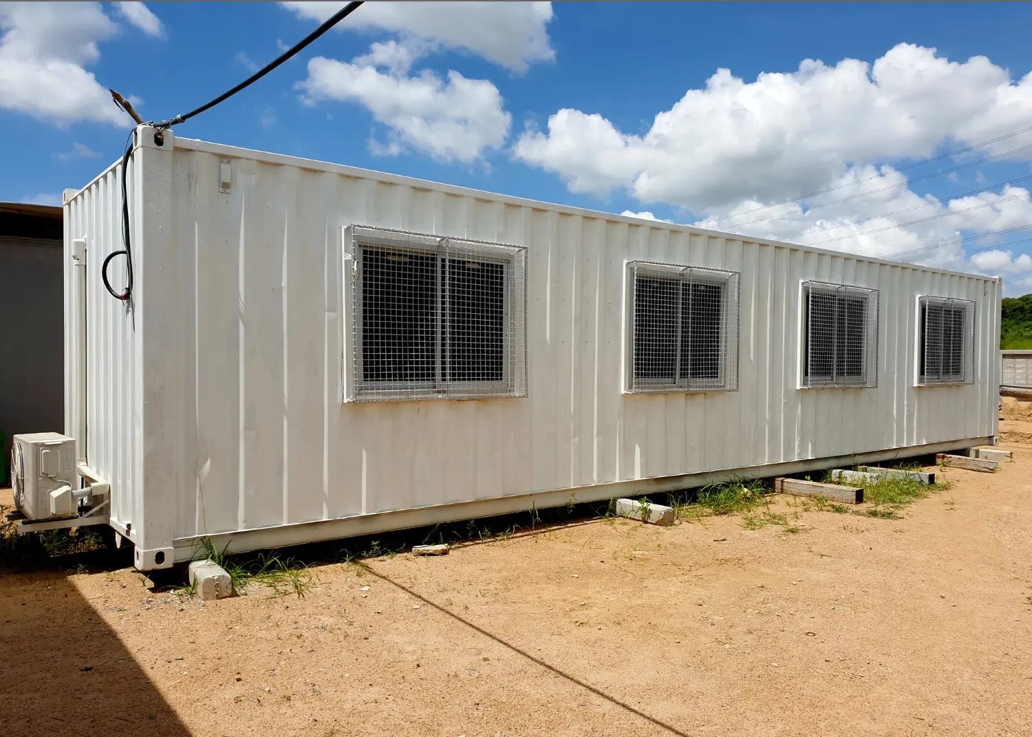 Contêiner adaptado para habitação, com estrutura metálica e proteção nas janelas. Exige inspeção quanto à inflamabilidade dos materiais internos e desempenho térmico conforme NBR 15575.