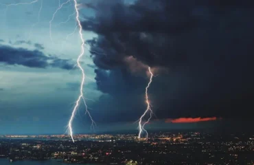 Manutencao-Sistema-SPDA relâmpago sobre cidade simbolizando a proteção do sistema SPDA