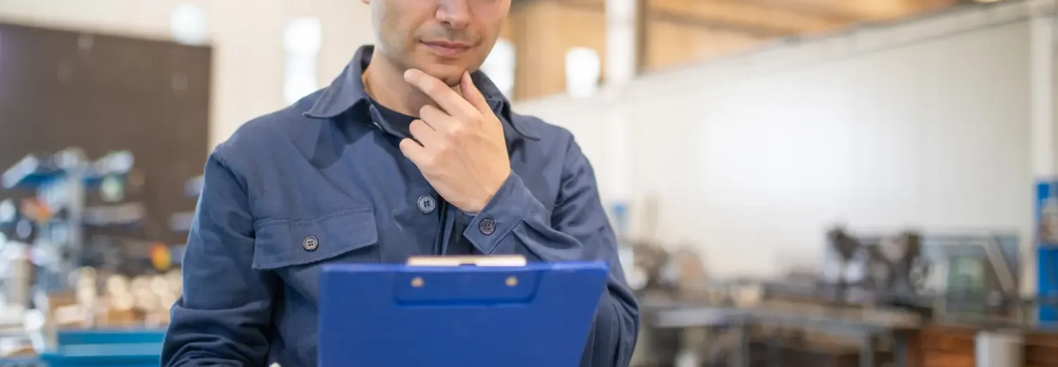 Trabalhador analisando um documento de parecer técnico em uma grande instalação industrial