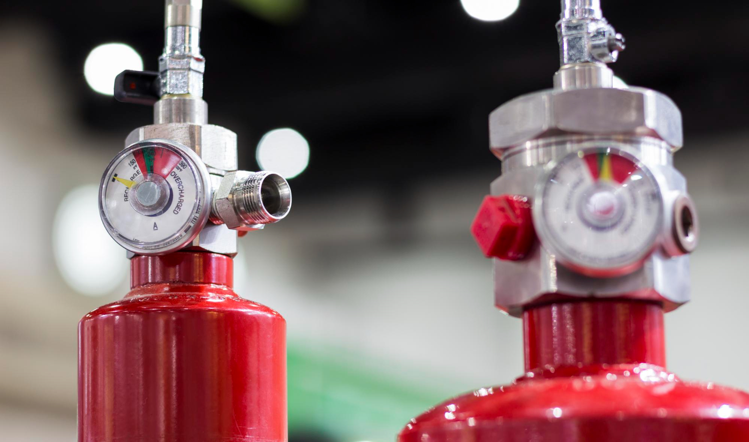 Cilindros de agente extintor com válvulas equipadas com manômetros, componentes essenciais nos sistemas fixos de gases para combate a incêndio. - Curso IT-26.