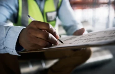 relatorio-tecnico Engenheiro escrevendo em uma prancheta as verificações feitas em relatório técnico durante inspeção