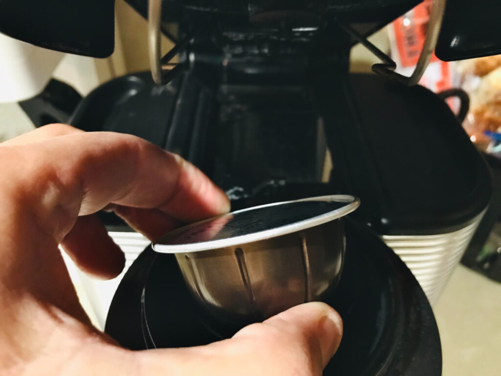 Inserção manual de cápsula em máquina de café: etapa crítica que exige cuidado para evitar falhas no sistema de perfuração e garantir a extração adequada da bebida. - Curso Manutenção Máquina de Café.