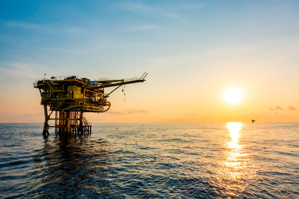 Operação de guindaste offshore durante a transferência de pessoal com cesto (man-riding). A cena destaca a importância da comunicação entre operador e equipe, além do cumprimento rigoroso das normas de segurança marítima e uso de EPI adequado.