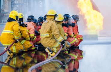 Curso Brigada Incêndio NBR 14276 Inglês Brigadistas em ação tática contra fogo aberto. Técnica, sincronia e liderança silenciosa em movimento.