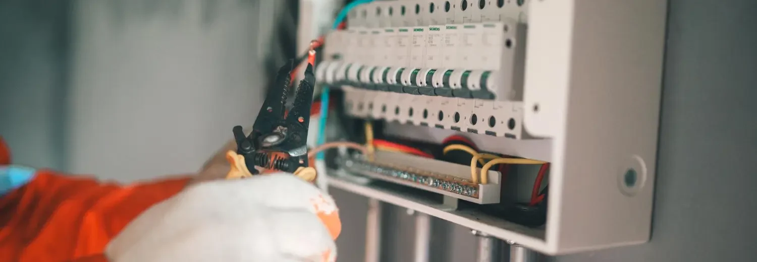 Técnico realiza decapagem de condutores em sistema de proteção com seccionamento visível. O painel está identificado e isolado, como exige o prontuário da instalação elétrica.