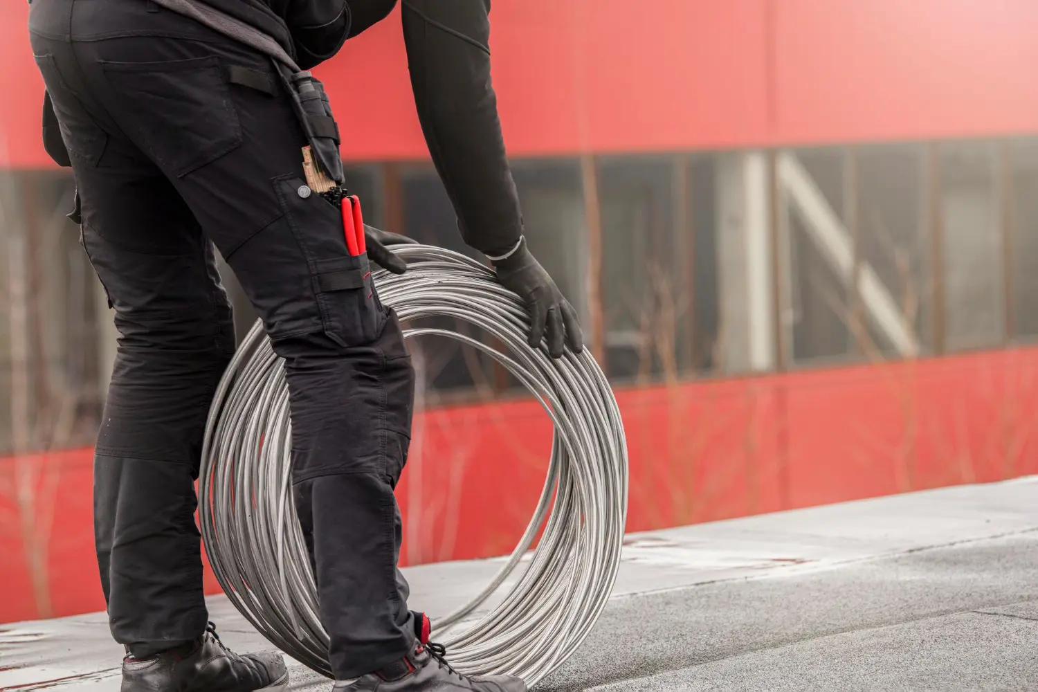  Manipulação controlada de cabo de alumínio nu para instalação em coberturas técnicas. O enrolamento adequado e o uso consciente do torque preservam a integridade estrutural do condutor.