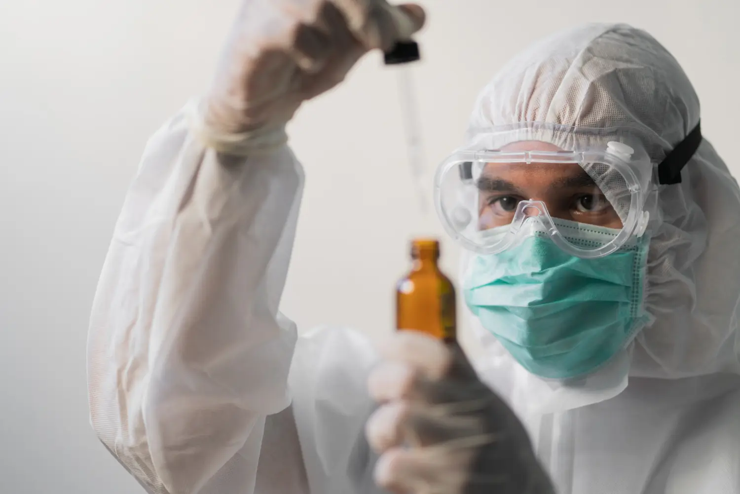 Manipulação controlada de substância química em laboratório, com proteção respiratória e ocular adequada.