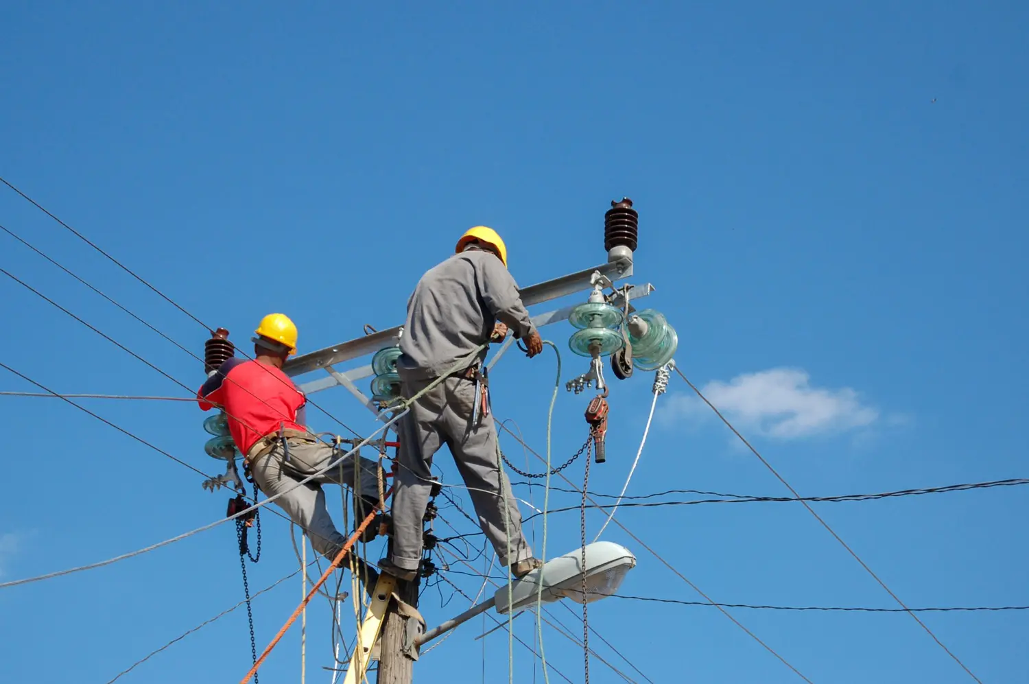 Técnicos eléctricos realizando intervención en estructuras energizadas en altura. Aplicación directa de las técnicas de trabajo en tensión bajo las exigencias de la NR 10 SEP