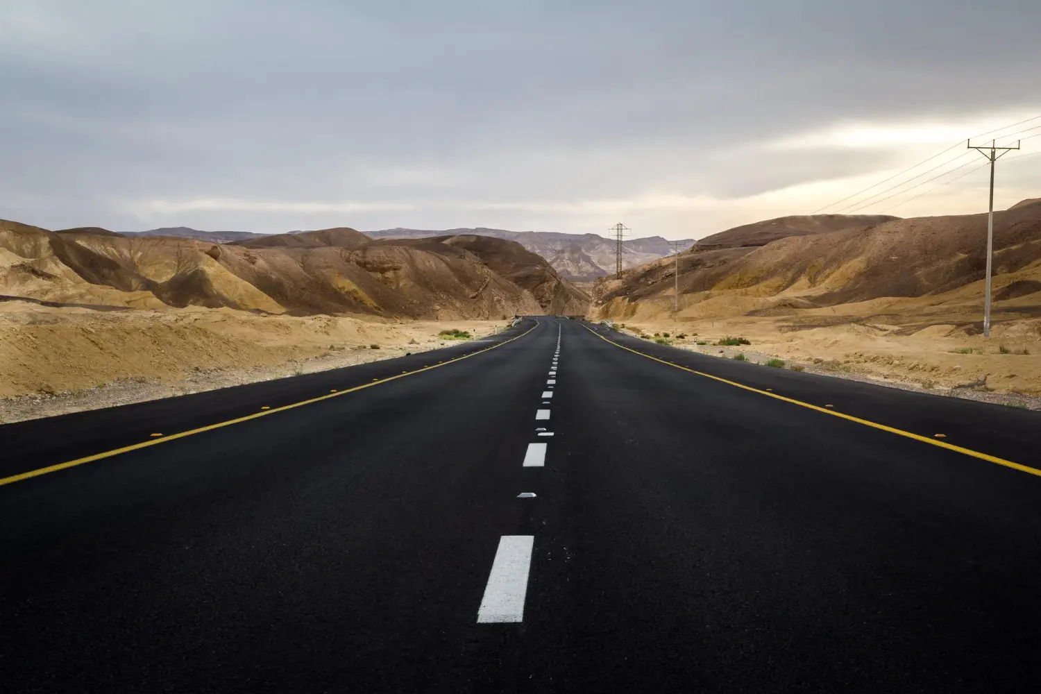 Trecho de rodovia em zona árida com faixa de domínio limpa e utilizada para passagem de infraestrutura elétrica – exemplo de uso multifuncional eficiente.