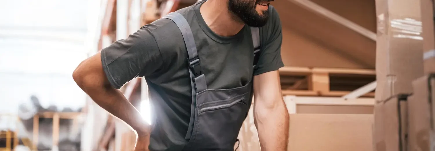 Operário com dor nas costas em fábrica devido a riscos ocupacionais relatados em laudo ergonômico