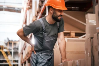 Operário com dor nas costas em fábrica devido a riscos ocupacionais relatados em laudo ergonômico
