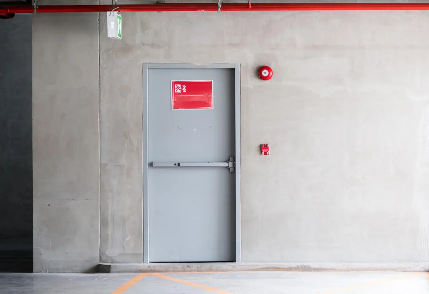 Porta corta-fogo em garagem com sinalização visível – manutenção evita falhas em áreas críticas.