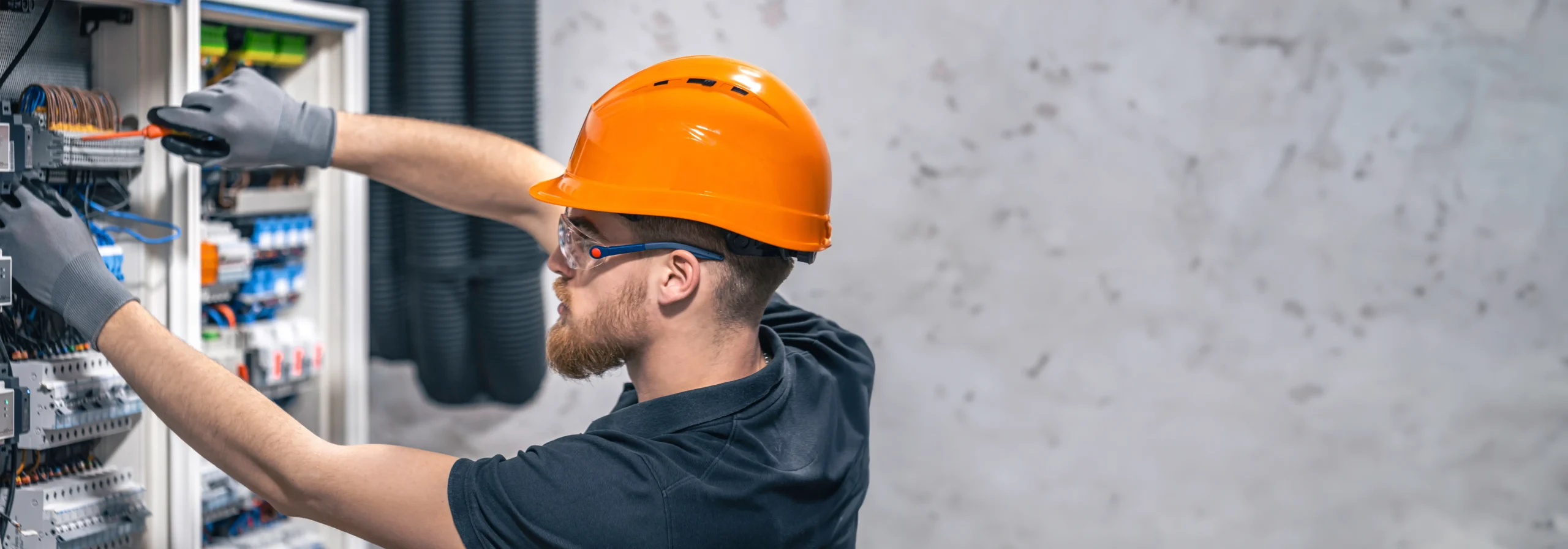 Eletricista ajustando componentes de baixa tensão em quadro elétrico seguindo práticas seguras.